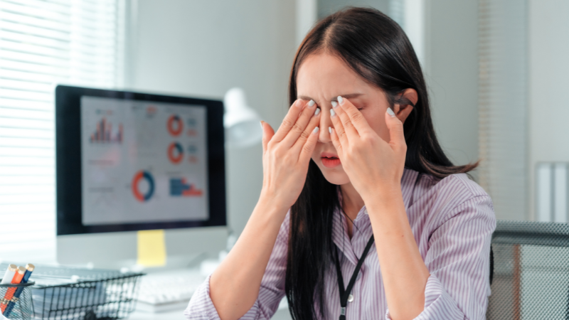 オフィスで目元を押さえている女性