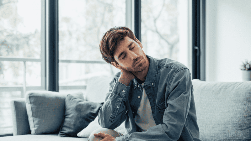 首の凝りを感じている男性