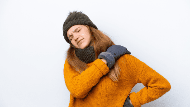 冬服を着て肩を抑える女性