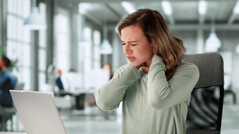 パソコンを前に首肩を抑える女性